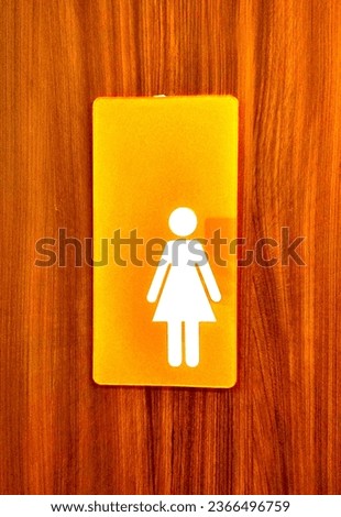 The orange women's toilet sign is attached to the front of the toilet door