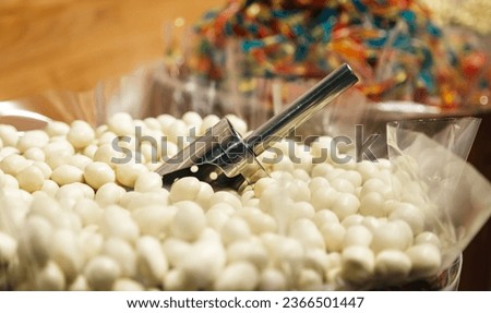 White and milk chocolate glazed candies, sweets in a candy shop, peanuts in white glaze on shop window.