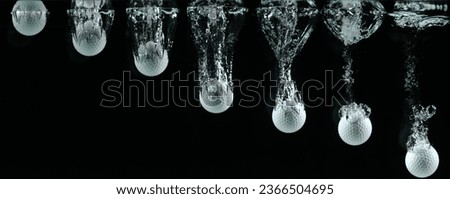Golf's Ball Falling into Water against Black background.