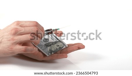 Syringe Falling into Hand with Dollars against White Background