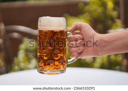 Pint of traditional czech pilsner beer, most famous and delicious kind of the beer in the europe and part of history of czech republic in the hand over the table. Picture is taken in summer evening.