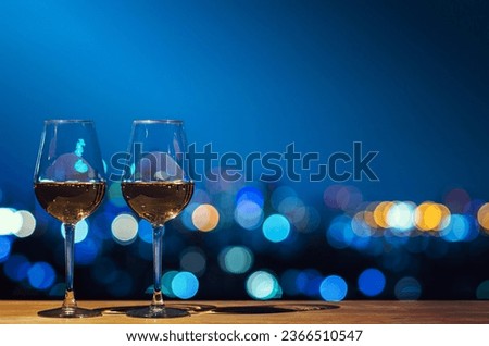 Two glasses of Rose wine with bokeh city colorful light from rooftop building.