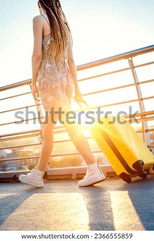 Woman walks around the city carrying a yellow suitcase. Tourist traveling