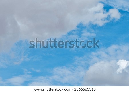 White fluffy cumulus clouds in blue sky. Horizontal photo for backgrounds and backdrops.