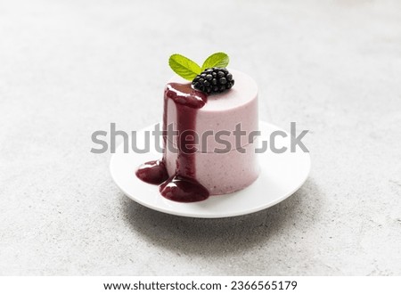 Modern dessert. Blackberry cream pudding, Panna Cotta with blackberry sauce,  cylindrical shape. Light background. Close up Royalty-Free Stock Photo #2366565179