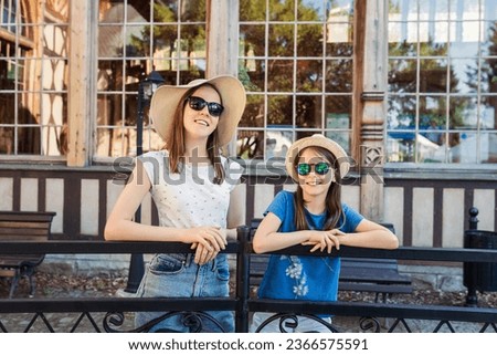 Portrait of two little girls in hats and sunglasses on the background of an old building
