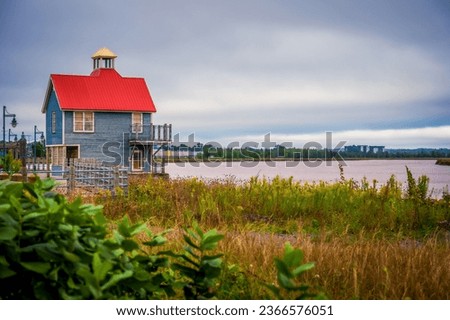Petitcodiac River and small building with red roof with dramatic sky, Bore Park, Moncton, New Brunswick, Canada. Photo taken in September 2023. Royalty-Free Stock Photo #2366576051