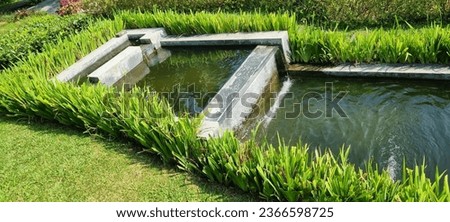 Landscape picture of two terrace pond with water flow from the upper, grass and small plants surround it