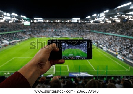 Taking picture of a football stadium during a match via smartphone.