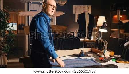 Experienced tailor designing fabric to mnaufacture custom made clothing items, craftsmanship concept. Small buisness owner creating clothes with expensive materials in atelier. Royalty-Free Stock Photo #2366605937