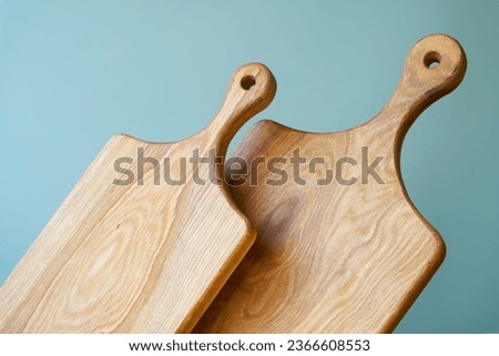 Two vintage natural wooden cutting boards made of solid oak with ovals on a mint green background. Rustic kitchen utensils. Photo. Daylight. Close-up