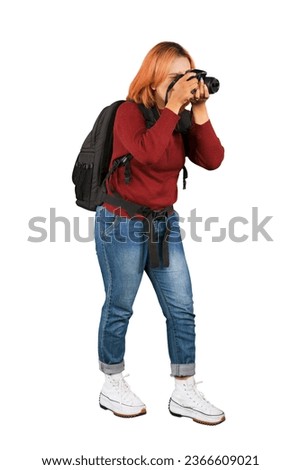 Young female photographer in casual winter clothes looking at viewfinder taking photos isolated over white background
