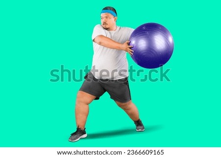 Overweight Man doing fitness exercise on pilates ball isolated on green background