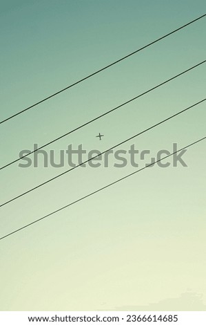 An airplane in the sky with four power lines forming a musical note-like scene. There's an artistic sense to it