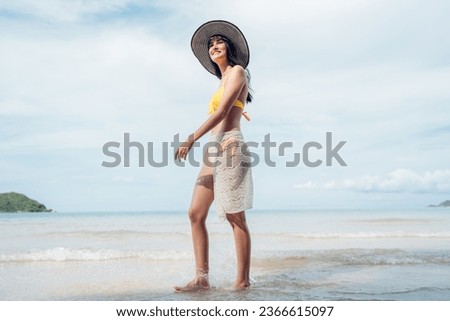 Beautiful woman in yellow bikini on tropical beach. Portrait of happy young woman smiling at sea. Brunette tanned girl in swimwear enjoying and walking on beach.