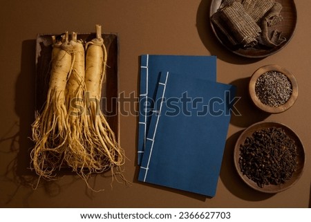 Traditional books decorated with Ginseng roots, Eucommia bark, Dried lavender and Cloves. Brown background. These herbs have been used for the treatment