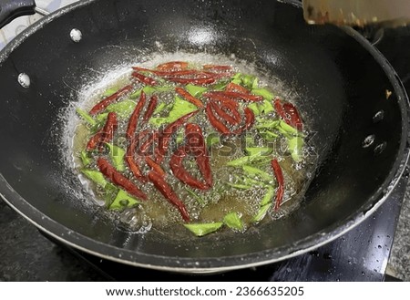 a photography of a frying pan with peppers and other food cooking, there is a pan with some food cooking on the stove.