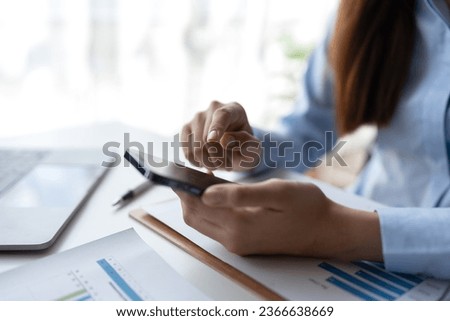 Happy young asian female accountant Positive concept using smartphone at her desk to relax with mobile application and use to chat business contact online marketing Excellent profit.