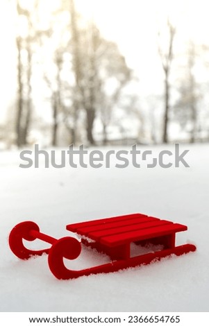 Small Red sled on snow background in beautiful winter day. Copy space for text. Mock up for product greeting card or wallpaper. Christmas
