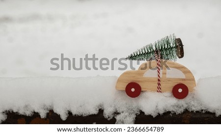 Wooden car carrying Christmas tree over snow. Copy space for text Toy car in snowy landscape. Merry Christmas and Happy New Year concept