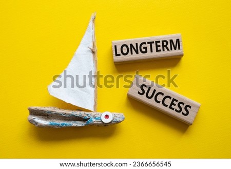 Longterm success symbol. Wooden blocks with words Longterm success. Beautiful yellow background with boat. Business and Longterm success concept. Copy space.
