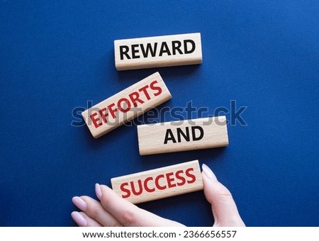 Reward Efforts and Success symbol. Concept words Reward Efforts and Success on wooden blocks. Beautiful deep blue background. Businessman hand. Business concept. Copy space.
