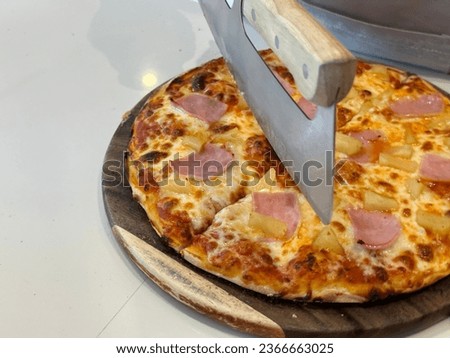 Closeup chef cuts freshly prepared pizza slices. Hand of chef baker in white uniform cutting pizza at kitchen. Pizza picture free space for text.