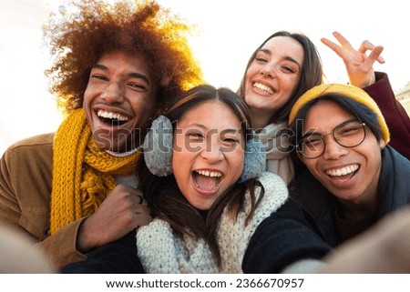 Happy multi-ethnic friends having fun outdoors. Multiracial young group of people taking selfie looking at camera.
