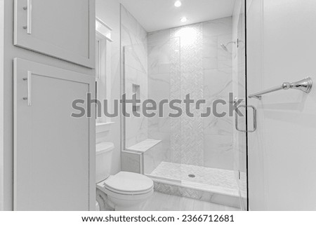 Clean Modern Primary Bathroom Glass Shower with Tile Walls and Grey Cabinetry. Stone Bench with Built In Shelves Royalty-Free Stock Photo #2366712681