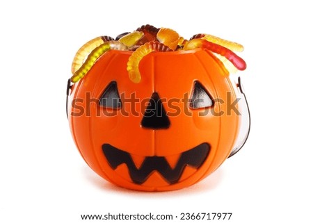 Sweets gummy worms candies in Halloween bag basket jack o lantern pumpkin isolated on white background