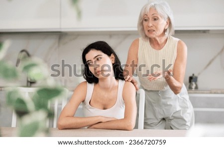 Elderly woman during family quarrel with young woman in kitchen at home Royalty-Free Stock Photo #2366720759