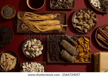 The red background featured a lot of traditional herbal medicine types placed on wooden dishes. A tonic bowl displayed. For medicine advertising with top view