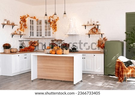 Autumn kitchen interior. Red and yellow leaves and flowers in the vase and pumpkin on light background