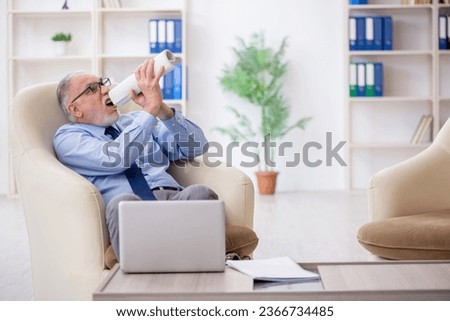 Old male employee sitting on arm-chair