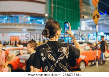 Girl takes pictures of the city on a phone. Tourist near attractions. A traveler uses a digital gadget for photos, night life