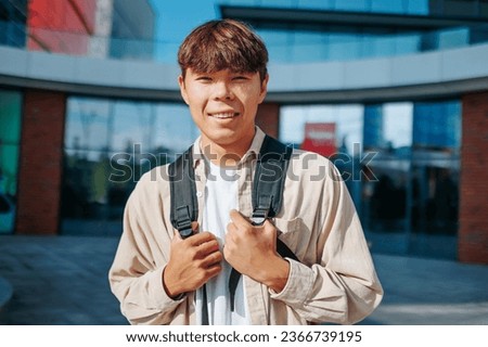 This genuine portrait showcases the smiling face of a young Asian Korean student boy, a picture of pure happiness. With his schoolbag by his side, he embodies the joy of learning looking at camera