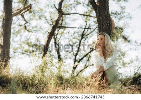 girl artist, woman paints picture landscape, summer forest, denim shorts, creating creativity artistic mood. Blank white canvas getting started. Grass trees background. 