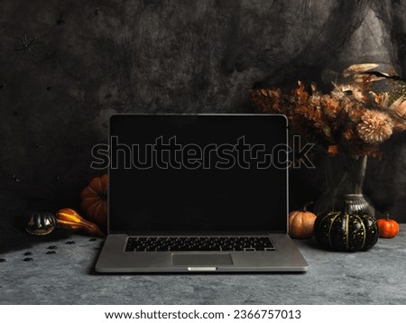 Halloween home office workspace with laptop screen. Cozy fall background with web and spiders, pumpkins