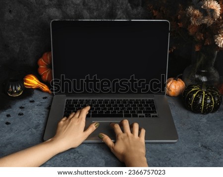 Halloween home office workspace with laptop screen. Cozy fall background with web and spiders, pumpkins