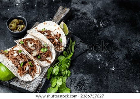 Pork carnitas tacos on corn tortillas with onion and lime. Black background. Top view. Copy space.