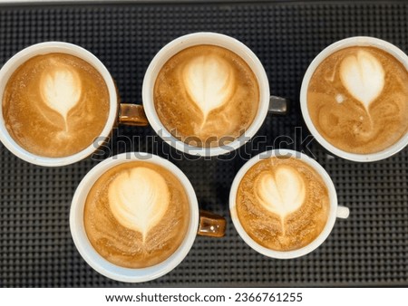Coffee cups with latte art on the black table.