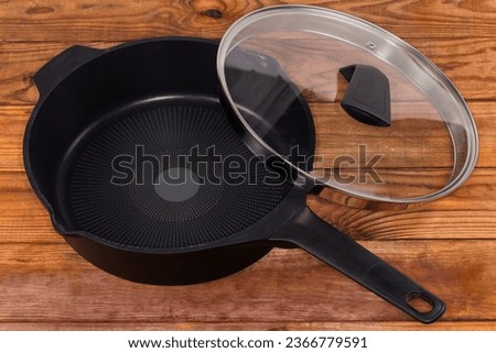 Empty deep frying pan made of cast aluminum with titanium non-stick coating with partly removed lid of glass and stainless steel on the rustic table
 Royalty-Free Stock Photo #2366779591