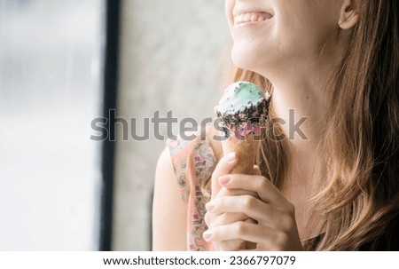 Close up Women eat icecream cone chocolate mint with smiling face. Happy women enjoy sweet dessert hand holding frozen icecream. Close up hand enjoy gelato in cafe. Happy smile lifestyle headshot