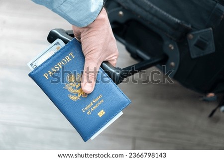 a man's hand with an American passport and luggage in close-up. The concept of migration and travel. Foreign trips. Flights in the United States of America Royalty-Free Stock Photo #2366798143