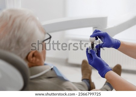 Professional dentist man treating cavities for a old man at the modern clinic he wearing special glasses for this treatment Royalty-Free Stock Photo #2366799725