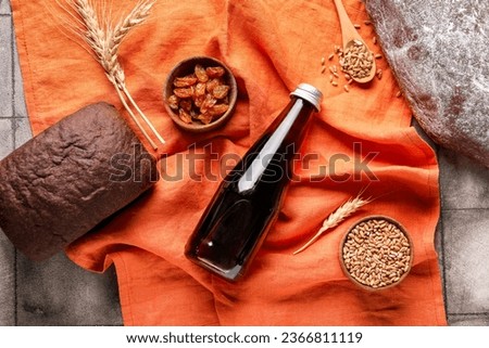 Bottle of tasty kvass, wheat grains, bread and raisins on table
