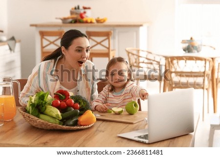 Little girl with her mother eating apples in kitchen