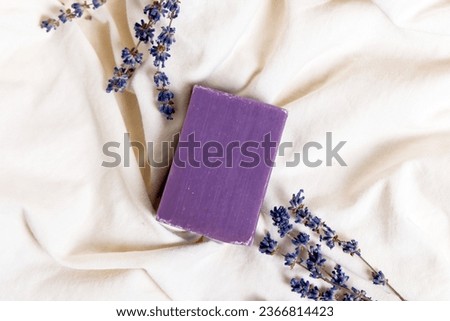 lavender handmade soap isolated on light background, on bed sheet with flowers and purple sack for sleeping improvement.soap on woman hand, woman holding bouquet.minimalist product photography. Royalty-Free Stock Photo #2366814423