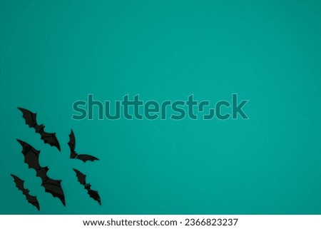 Turquoise background with bats in the lower left corner. copy space. Halloween