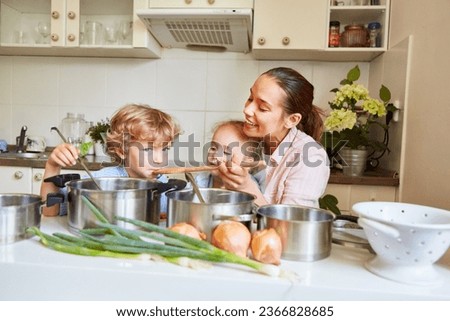 Smiling woman enjoying with son and daughter while preparing soup in kitchen at home Royalty-Free Stock Photo #2366828685